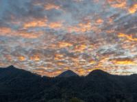 Intensiv orange leuchtende Wolkenhaufen über dem Bergkamm mit Riesenberg dahinter